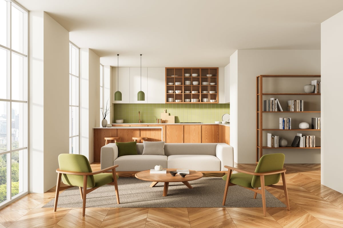 Open-plan living room and kitchen with green chairs and warm wood accents